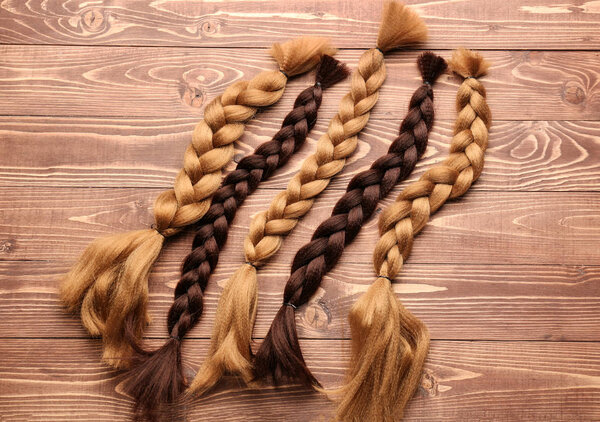 Braided strands on wooden background. Concept of hair donation