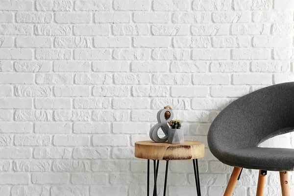 Armchair with table near white brick wall — Stock Photo, Image