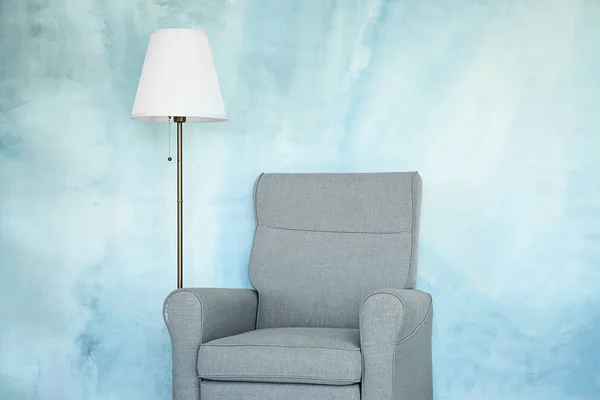 Poltrona con lampada vicino parete a colori — Foto Stock
