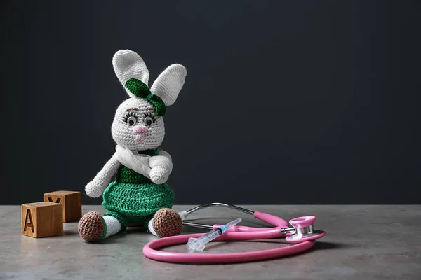 Cute bunny toy with stethoscope on grey table. Health care for kids — Stock Photo, Image