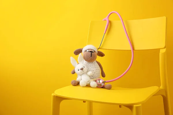 Милі іграшки зі стетоскопом на стільці на фоні кольору. Охорона здоров'я дітей — стокове фото