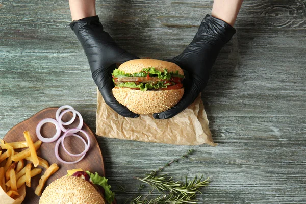 Mujer comiendo hamburguesa fresca en la mesa — Foto de Stock