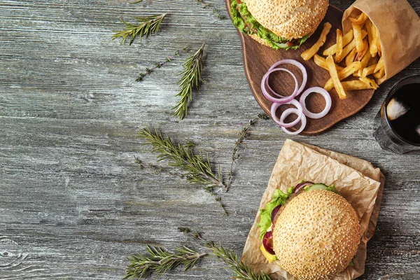 Вкусные свежие бургеры и картошка фри на деревянном столе — стоковое фото