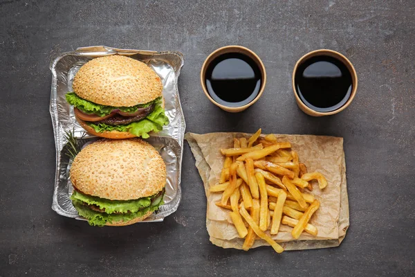 Tasty fresh burgers, cups of soda and french fries on table — Stock Photo, Image