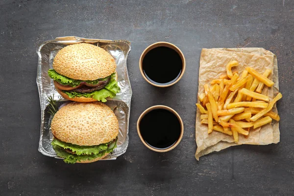 Tasty fresh burgers, cups of soda and french fries on table — Stock Photo, Image