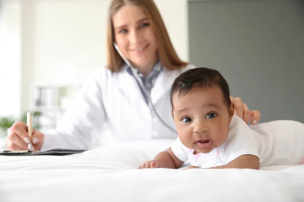 Pediatr vyšetřující afroamerické dítě na klinice — Stock fotografie