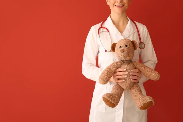 Pediatrician with toy on color background — Stock Photo, Image