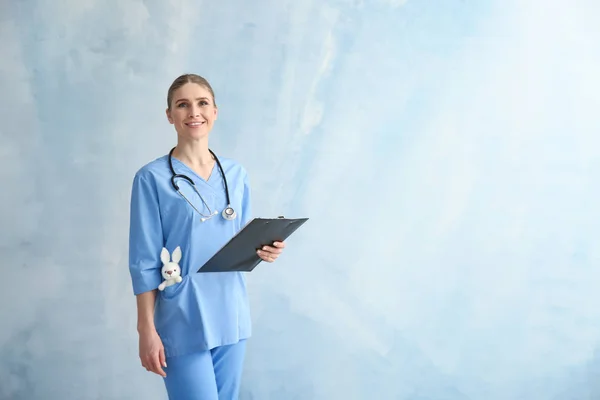 Pediatrician with clipboard on color background — Stock Photo, Image