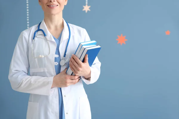 Female doctor with books on color background — Stock Photo, Image