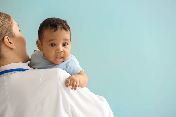 Kinderarts met Afro-Amerikaanse baby op kleur achtergrond — Stockfoto