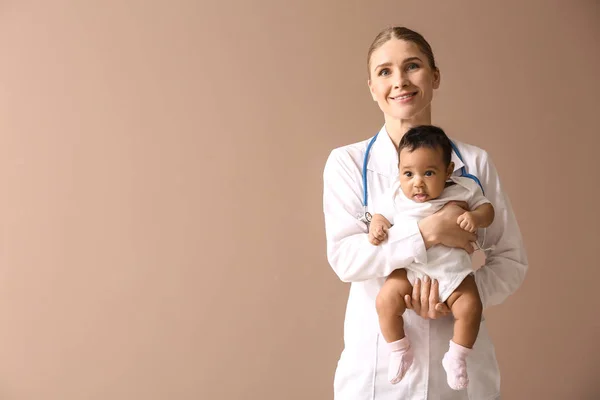 Kinderarts met Afro-Amerikaanse baby op kleur achtergrond — Stockfoto