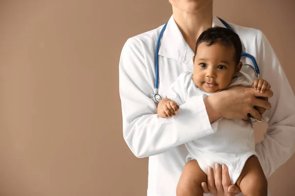 Lastenlääkäri, jolla on afroamerikkalainen vauva väritaustalla — kuvapankkivalokuva