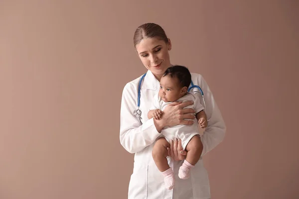 Pediatra com bebê afro-americano em fundo de cor — Fotografia de Stock