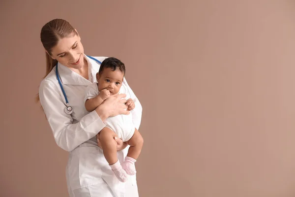 Kinderarzt mit afrikanisch-amerikanischem Baby auf farbigem Hintergrund — Stockfoto