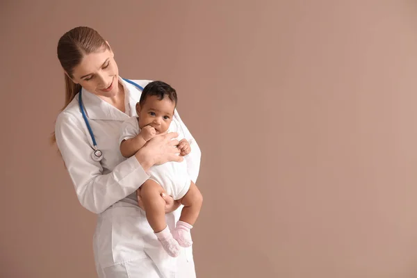 Kinderarts met Afro-Amerikaanse baby op kleur achtergrond — Stockfoto