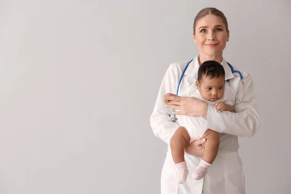 Kinderarzt mit afrikanisch-amerikanischem Baby auf hellem Hintergrund — Stockfoto