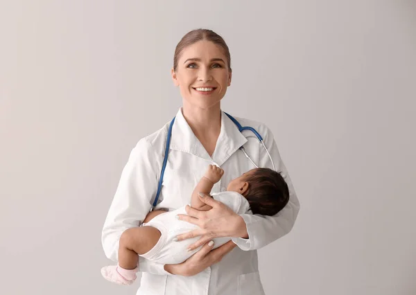 Pediatrician with African-American baby on light background — Stock Photo, Image