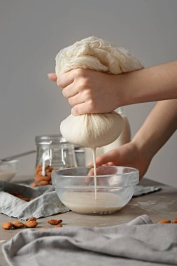 Woman making healthy almond milk in kitchen clipart