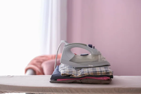 Iron with clean clothes on board — Stock Photo, Image