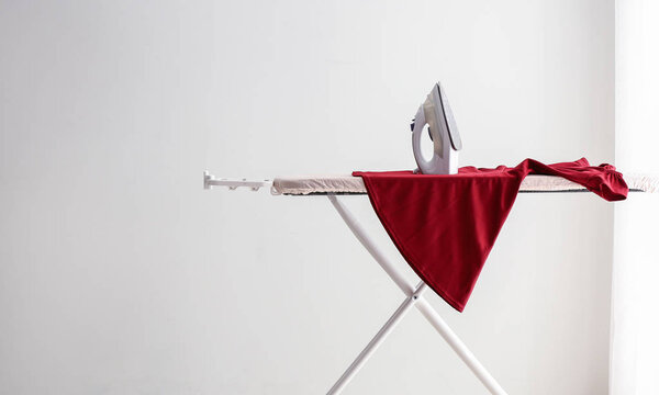 Гладильная доска с чистой одеждой в номере
