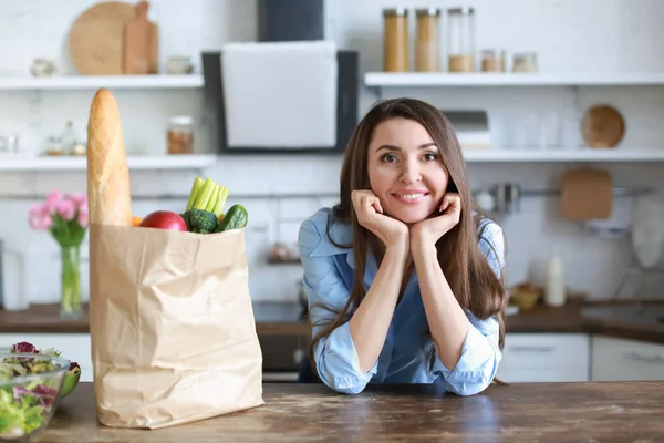 Beautiful woman with bag full of products in kitchen at home — Stock Photo, Image