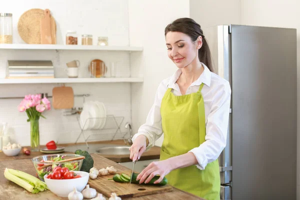 Beautiful woman cutting vegetables in kitchen at home — Stock Photo, Image