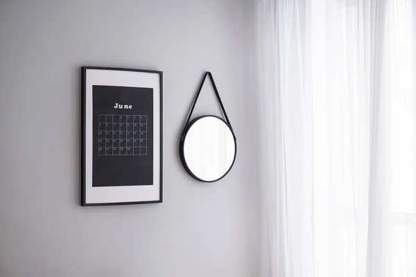 Calendar and mirror on wall in light room