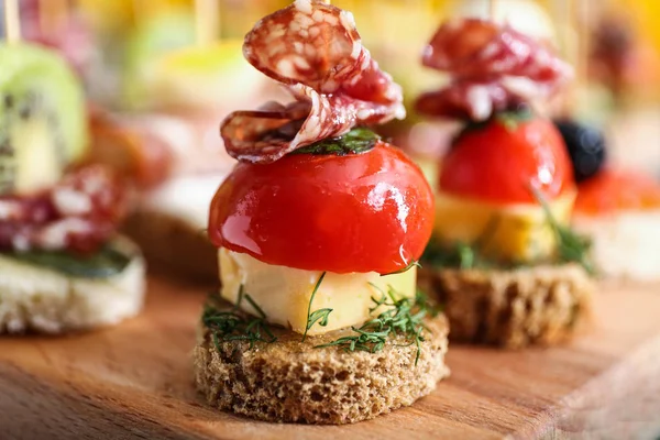 Tasty canapes on wooden board, closeup — Stock Photo, Image