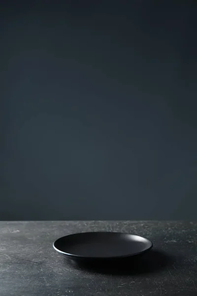 Placa na mesa contra fundo escuro — Fotografia de Stock