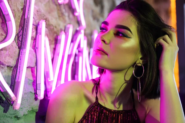 Toned portrait of beautiful young woman near neon lighting on wall — Stock Photo, Image