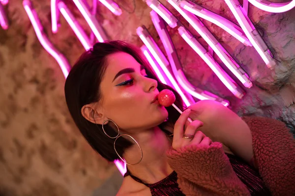 Portrait of beautiful young woman near neon lighting on wall — Stock Photo, Image