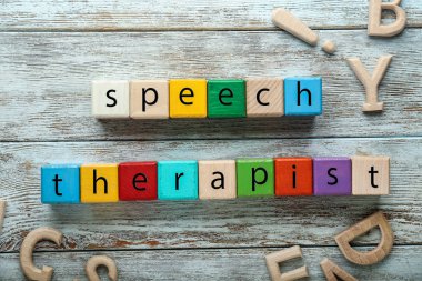 Cubes forming text SPEECH THERAPIST on wooden background clipart