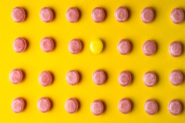 Renkli arka planda pembe olanlar arasında bir sarı şeker. Benzersizlik kavramı