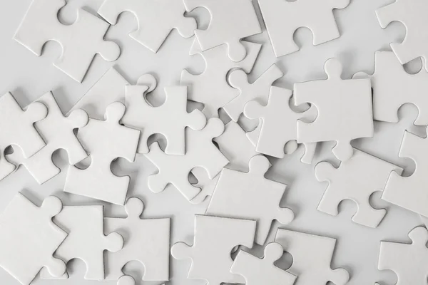 Hoop van witte puzzelstukjes op lichte achtergrond — Stockfoto