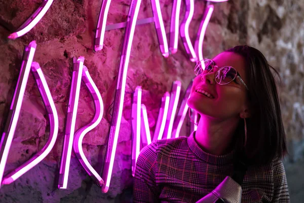 Toned portrait of beautiful young woman near neon lighting on wall — Stock Photo, Image