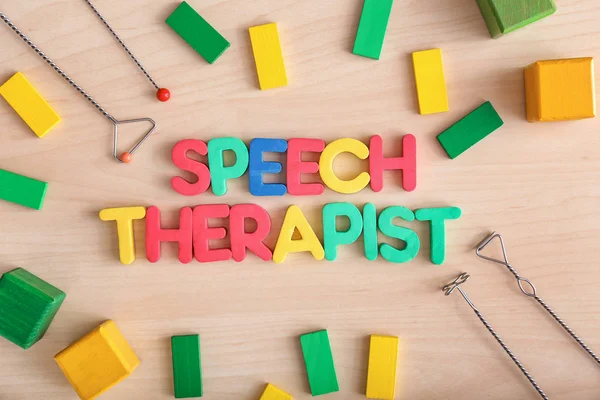 Composition with text SPEECH THERAPIST on wooden background — Stock Photo, Image