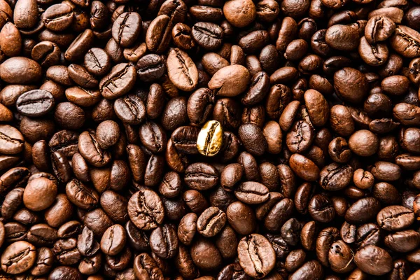 One golden coffee bean among brown ones, closeup. Concept of uniqueness — Stock Photo, Image