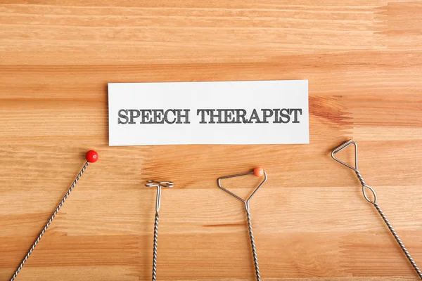 Logopedic probes and paper with text SPEECH THERAPIST on wooden background — Stock Photo, Image