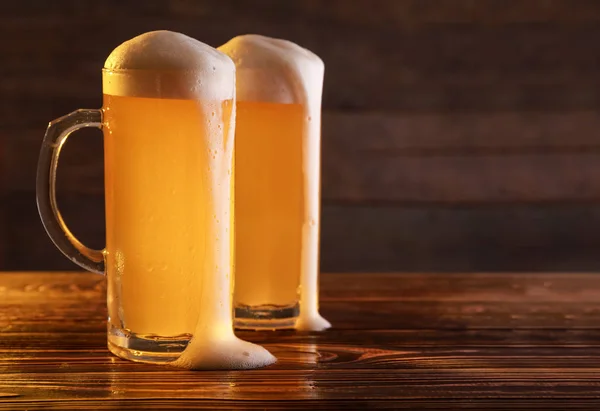 Mugs of fresh beer on wooden table — Stock Photo, Image