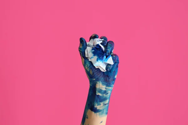 Painted female hand with crumpled paper on color background — Stock Photo, Image