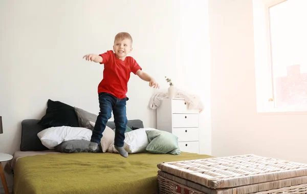 Feliz niño saltando en la cama en casa — Foto de Stock