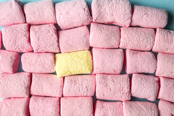 One yellow marshmallow among pink ones on color background, closeup. Concept of uniqueness — Stock Photo, Image