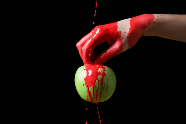Painted hand with apple against dark background