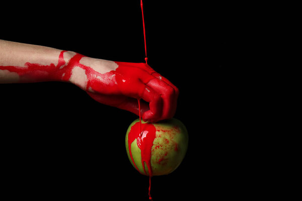 Painted hand with apple against dark background