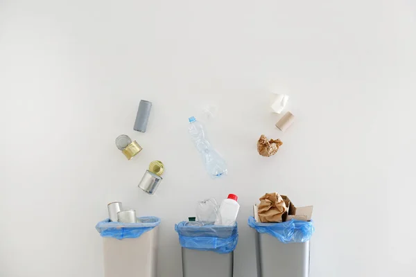 Garbage falling into trash bins on white background — Stock Photo, Image