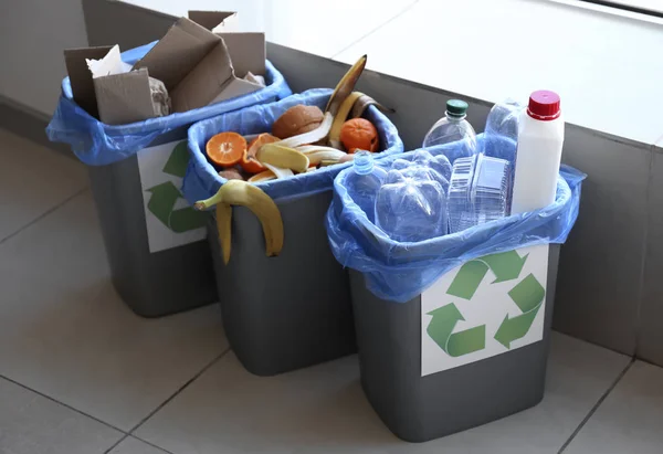 Trash bins with different types of garbage indoors — Stock Photo, Image