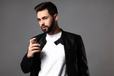 Yakışıklı adam gri arka plan üzerinde parfüm şişe