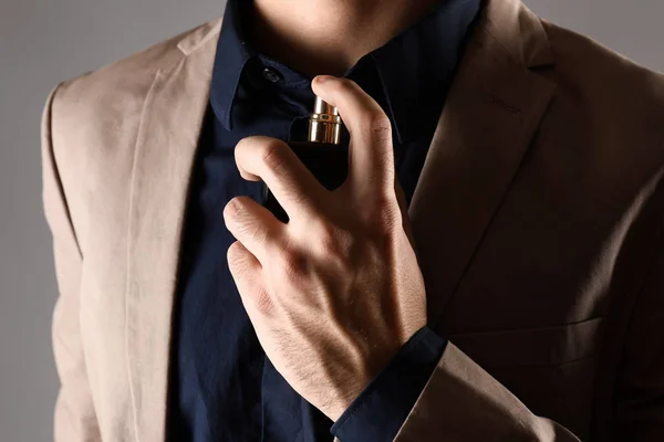 Handsome man with bottle of perfume on grey background, closeup — Stock Photo, Image