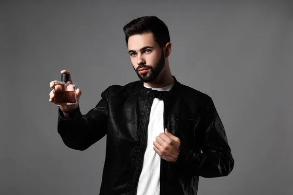 Hombre guapo con botella de perfume sobre fondo gris —  Fotos de Stock