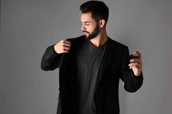 Hombre guapo con botella de perfume sobre fondo gris — Foto de Stock